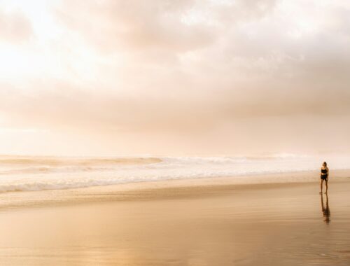 femme marchant seule au bord de l'océan symbolisant l'hypervigilance et l'anxiété chez les personnes sensibles – retrouver l’apaisement et la sécurité intérieure